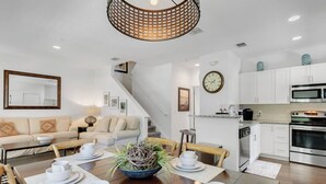 A modern kitchen with white cabinets, a stainless steel oven, and a dining area with a wooden table set for four.
