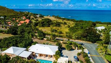 A residential area with houses, a swimming pool, and a road leading to the ocean.
