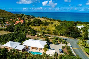 A residential area with houses, a swimming pool, and a road leading to the ocean. - Modern home, w/ pool & 2-mins to beach! (Christiansted)
