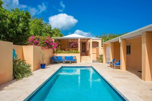 A swimming pool with a sun terrace, lounge chairs, and a covered seating area. - Modern home, w/ pool & 2-mins to beach! (Christiansted)