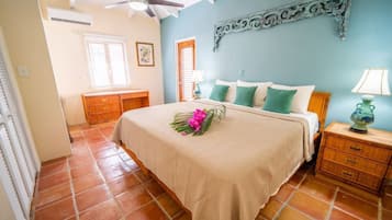 A bedroom with a bed, nightstands, a ceiling fan, and a decorative wall piece.