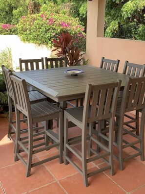 Una mesa rectangular al aire libre con seis sillas, rodeada de baldosas de terracota.