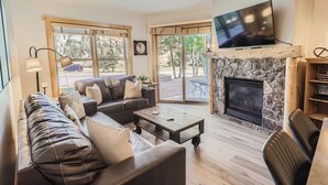 A modern living room with a stone fireplace, leather sofas, a coffee table, and a flat-screen TV. - Upscale Luxury-Next to Slopes/Golf, View, Hottub (Copper Mountain)