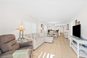 A living room with a sofa, a television, and a dining area with a table and chairs.