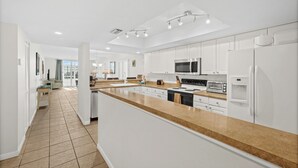Cozinha moderna com armários brancos, uma ilha grande e eletrodomésticos embutidos.