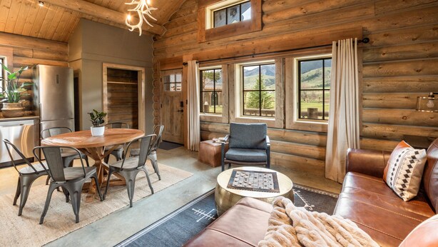 A log cabin interior with a dining area, seating, and a fireplace. - Beautiful Log Cabin Near Fishing Access To Yellowstone (Livingston)