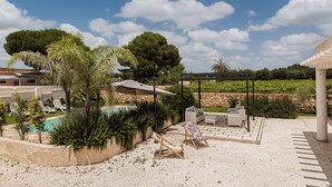 Un espace piscine comprenant des chaises longues, une pergola et un mur en pierre.