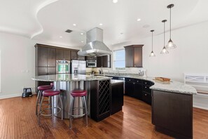 A modern kitchen with a central island, stainless steel appliances, and pendant lighting. - 🌊4BR Villa del Mar | Pet Friendly | Beautiful Ocean View | Walk to the Beach🌊 (New Smyrna Beach)