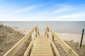 A wooden boardwalk leading to a beach with a clear view of the ocean.