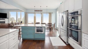 A spacious kitchen with a central island, stainless steel appliances, and a view of the outdoors. - Custom Lake Michigan Beachfront Vacation Home (Manistee)