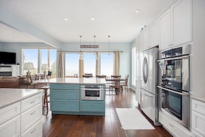 A spacious kitchen with a central island, stainless steel appliances, and a view of the outdoors.