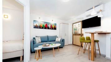 Un salon moderne avec un canapé bleu, une petite table ronde et deux chaises en bois.