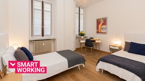 A modern hotel room with two beds, a desk, and a chair.