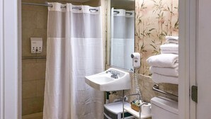 Un baño con ducha, inodoro, lavamanos y toallero.