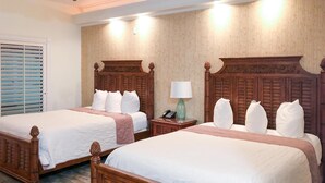 Una habitación de hotel con dos camas de madera, una mesita de noche con lámpara y una ventana con persianas.