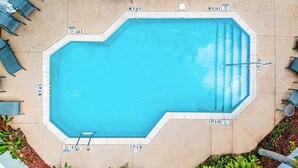 Una piscina octagonal con agua cristalina, rodeada de sillas de descanso y sombrillas.