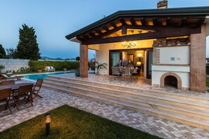 A covered outdoor patio with a pool, dining area, and fireplace.