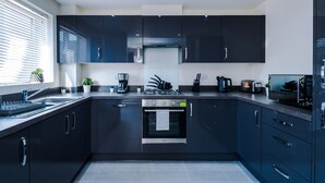 A modern kitchen with dark cabinetry, a built-in oven, and a gas stove. - 3 Bedroom House with River Irwell view, sleeps 6 (Salford)