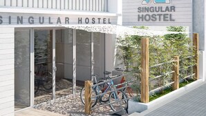 Entrada de un hostal con puerta de vidrio, un aparcamiento para bicicletas y un cartel que dice 'SINGULAR HOSTEL'.