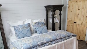 Ein Schlafzimmer mit einem Bett, einem Nachttisch, einem Kleiderschrank und einem gemusterten Teppich.