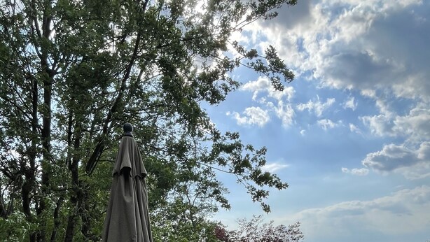 Een terras met een bank en stoelen, een pergola en uitzicht op het landschap.