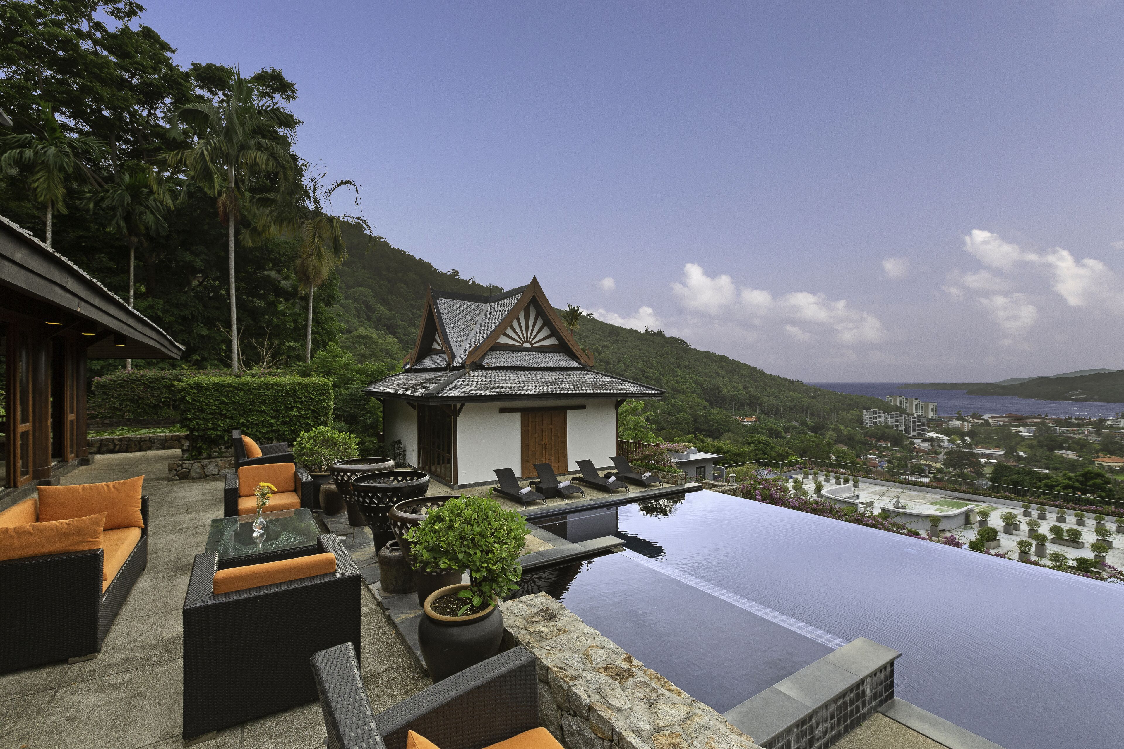 A rooftop infinity pool with outdoor seating and a view of the city.