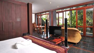 A hotel room with a bed, a television, a desk, and a wicker chair.