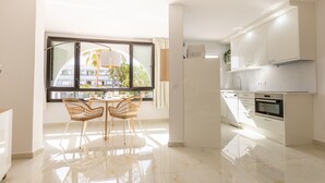 A modern kitchen with white cabinets, a built-in oven, and a dining area with a table and chairs.