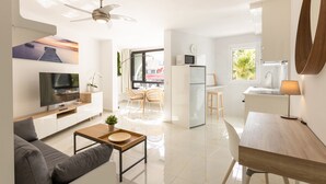 A modern hotel room with a living area, kitchenette, and a view of the outside.