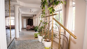 A hallway with a marble floor, potted plants, a brass railing, and a sign reading "ROOM". - Villa Aurora (Varna)