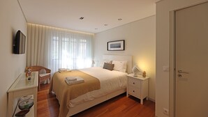A modern bedroom with a large bed, bedside tables, a desk, and a chair. - FLH Sá da Bandeira Modern Apartment (Oporto)