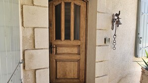 A wooden door with a 'WELCOME' mat in front, set in a stone archway.