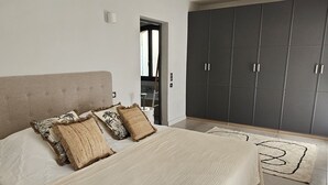 A bedroom with a large bed, a wardrobe, and a bathroom visible through an open door.