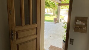 A wooden door leading to an outdoor patio area with a tiled floor and a potted plant.
