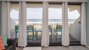 A balcony with a view of the beach, featuring a sofa and a table with chairs. - Island Winds E205-Park The Car & Forget It! Location X3! OMG View! (Gulf Shores)