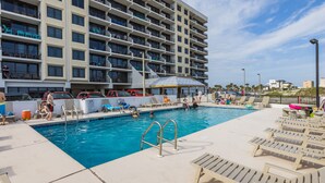 A hotel pool area with a large building in the background, a diving board, and lounge chairs. - Island Winds E205-Park The Car & Forget It! Location X3! OMG View! (Gulf Shores)