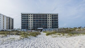 A modern hotel with multiple floors and balconies, situated on a sandy beach with a clear sky. - Island Winds E205-Park The Car & Forget It! Location X3! OMG View! (Gulf Shores)