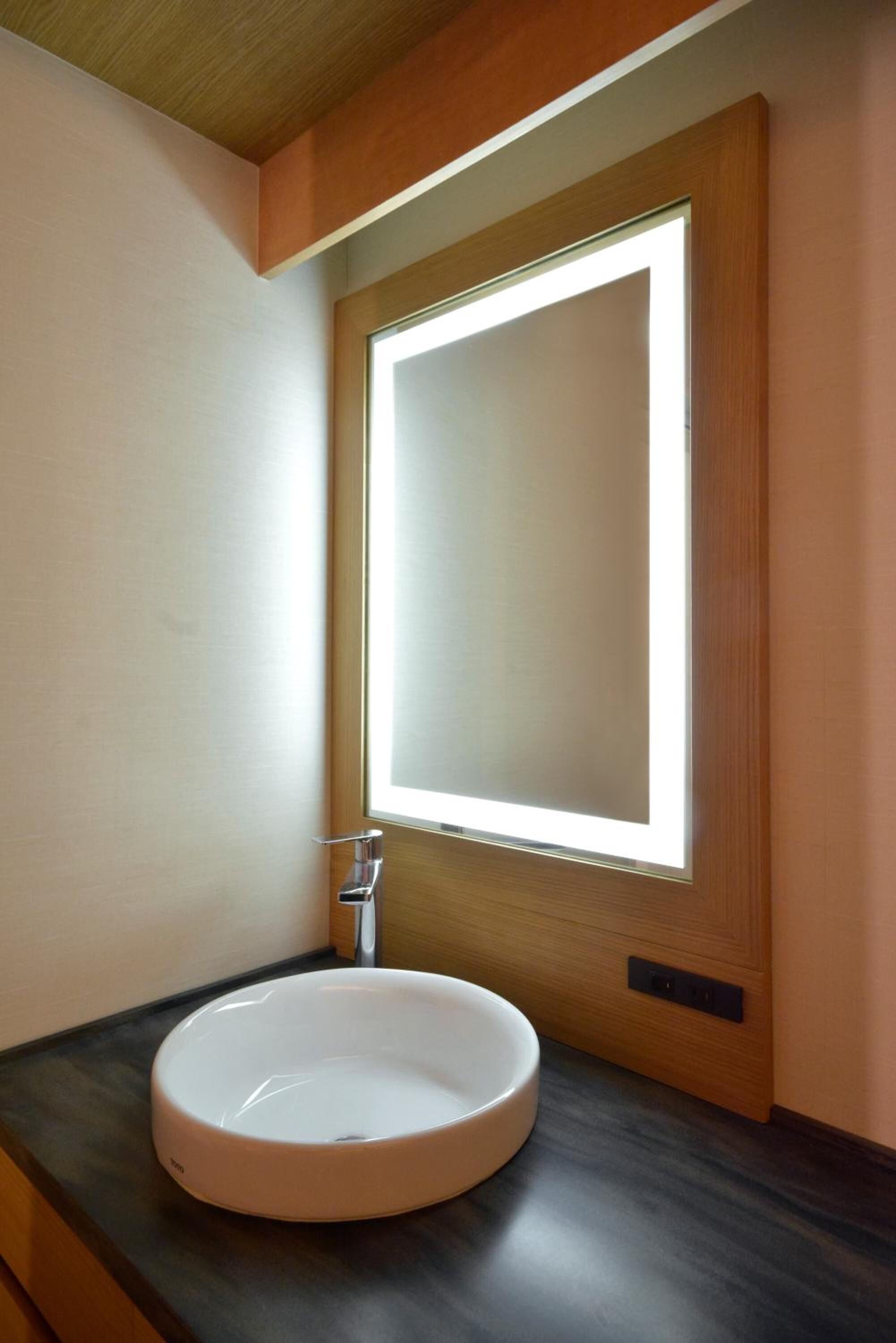 Ein Badezimmer mit einem runden Waschbecken, einem Spiegel und einer Holzeinrichtung.
