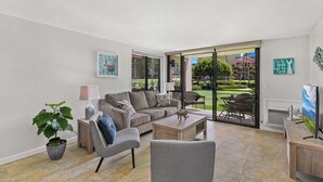 Un salon moderne avec un canapé, un fauteuil, une table basse et un téléviseur posé sur un meuble.