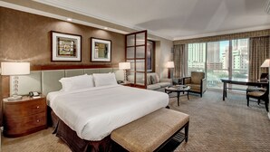 A hotel room with a large bed, a desk, a chair, a sofa, and a view of the city. - MGM Signature Balcony Suite 2817 NO RESORT FEE (Las Vegas)