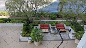 An outdoor seating area with red sofas, a small table, and planters. - MGM Signature Balcony Suite 2817 NO RESORT FEE (Las Vegas)