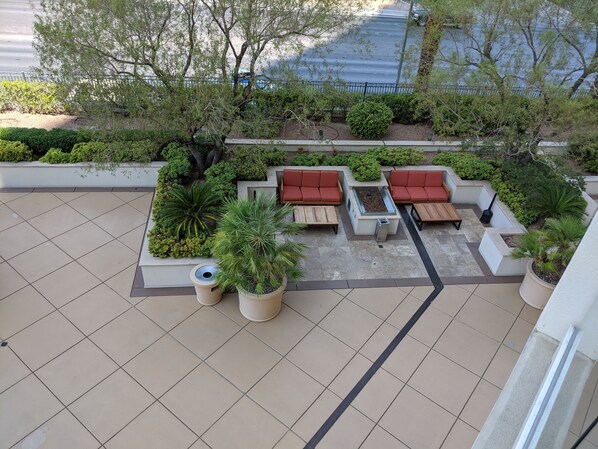 Un espace extérieur aménagé avec des canapés rouges, une petite table et des jardinières.