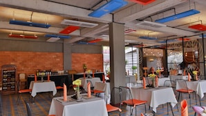 Un restaurante con mesas dispuestas para comer, paredes de ladrillo y luces colgantes.