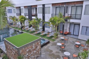 A modern hotel courtyard with a swimming pool, lounge chairs, and outdoor seating. - Central Corner D Angkor (Siem Reap)