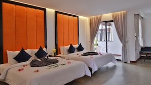 Habitación de hotel con dos camas, cada una con cubrecama y almohadas blancas, y un cabecero grande color naranja.