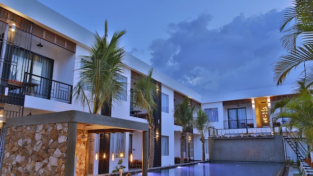 Un hotel moderno con piscina, pared de piedra y zona de estar al aire libre.