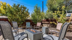 An outdoor patio with metal chairs and a square table, surrounded by a wooden fence and trees. - Greenlaw Getaway | 3BR | Spend Spring in Flagstaff! (Flagstaff)