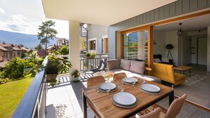 A dining area with a table set for four, outdoor seating, and a view of the surrounding landscape.