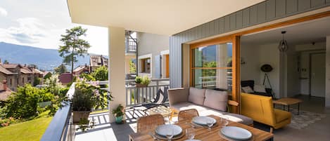 A dining area with a table set for four, outdoor seating, and a view of the surrounding landscape.