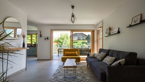 A spacious living room with a dark sofa, a yellow armchair, and a patterned rug.